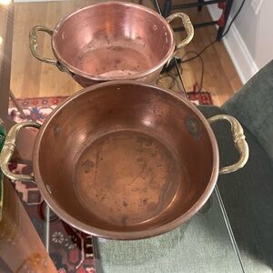 Two copper bowls with brass handles.
